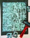 Letterpress printing block with letter stamps and a roller on a black background