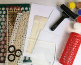 Collage of various craft supplies including a brayer, stamps, and paint on a white background.